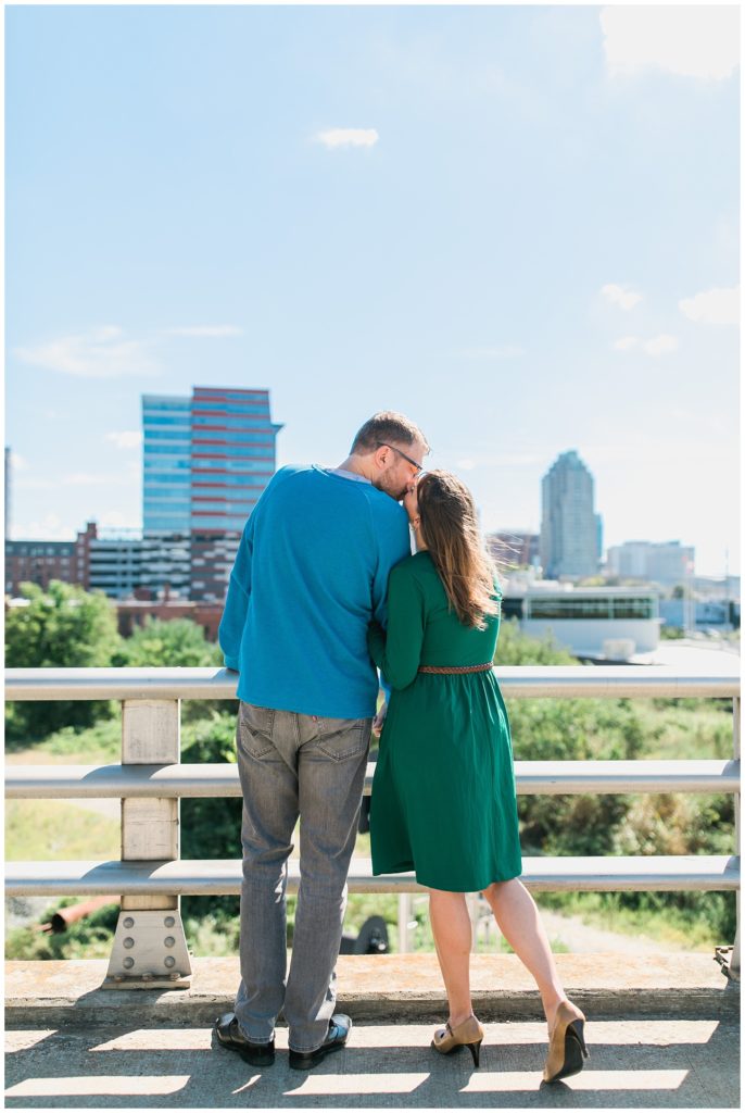 couple kissing in front of raleigh skyline
