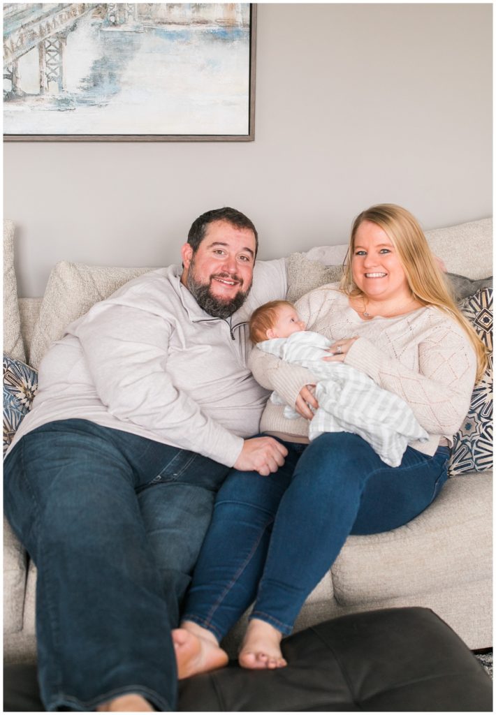 Family smiling with newborn on couch