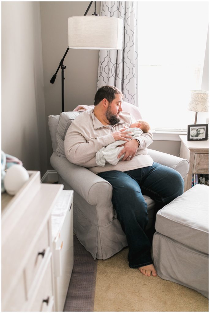 dad holding daughter in nursery newborn