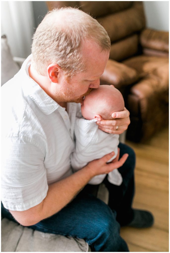 Dad kissing newborn son on the head