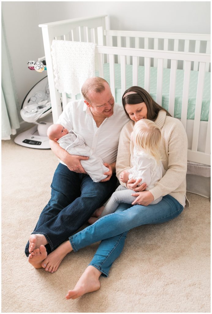 family with newborn and daughter on floor in nursery
